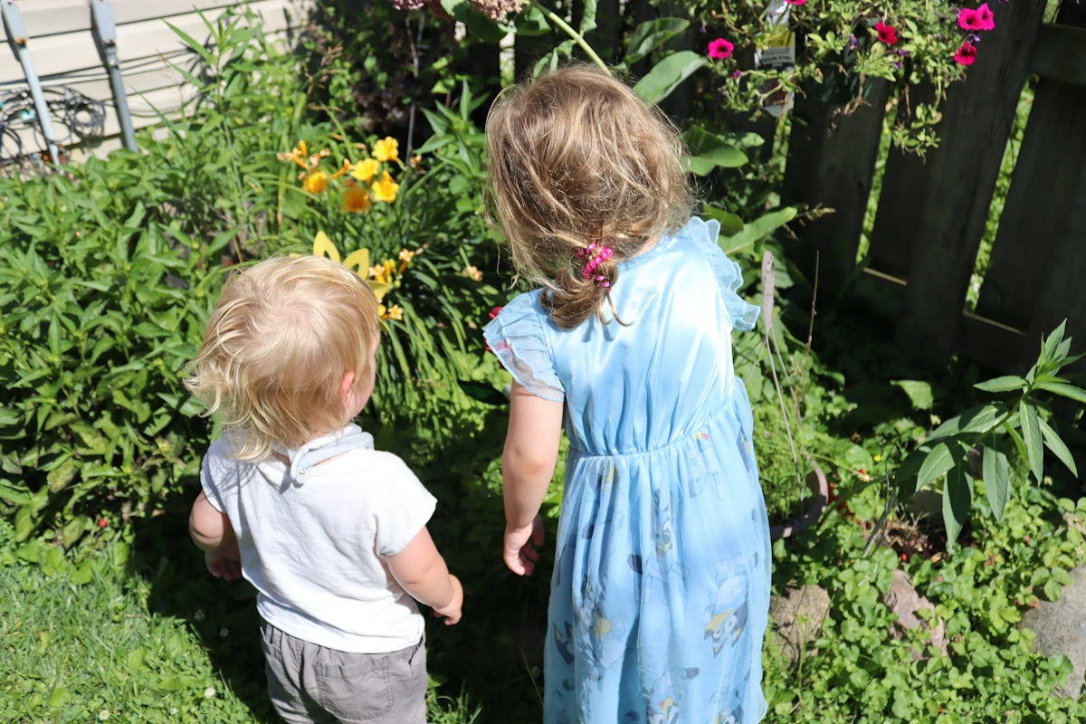 Two young children explore a lush garden.