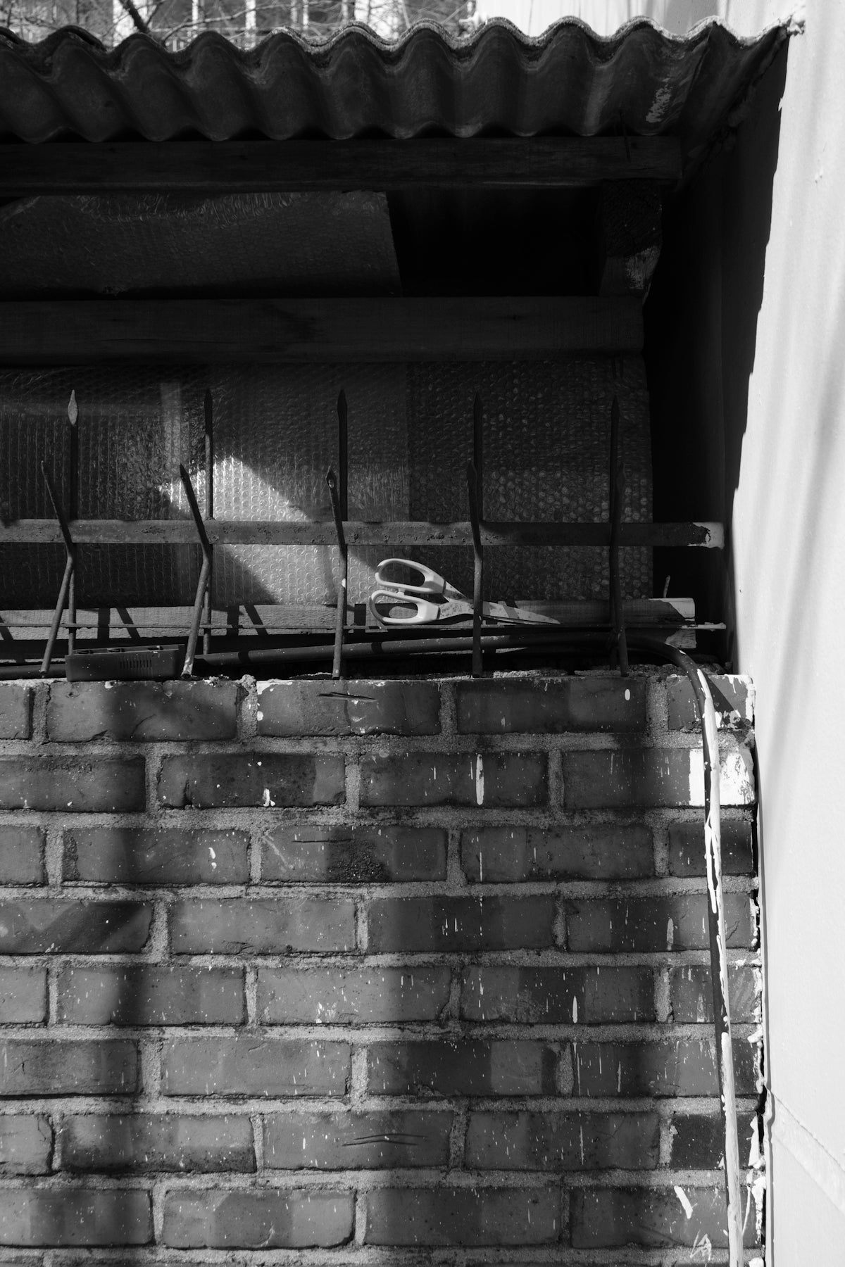 Brick wall with corrugated metal roof and scissors.