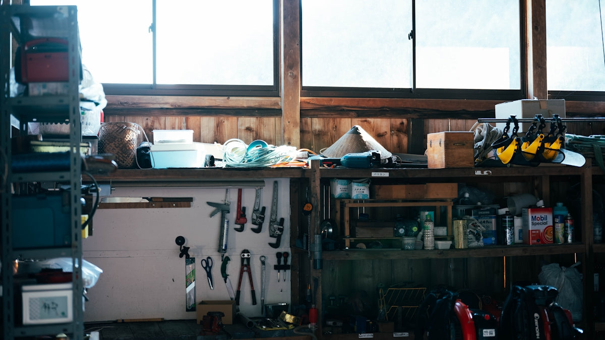 A cluttered workshop shelf with tools and supplies.