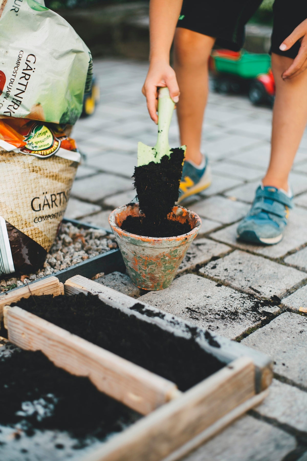 person putting soil inside brown planter