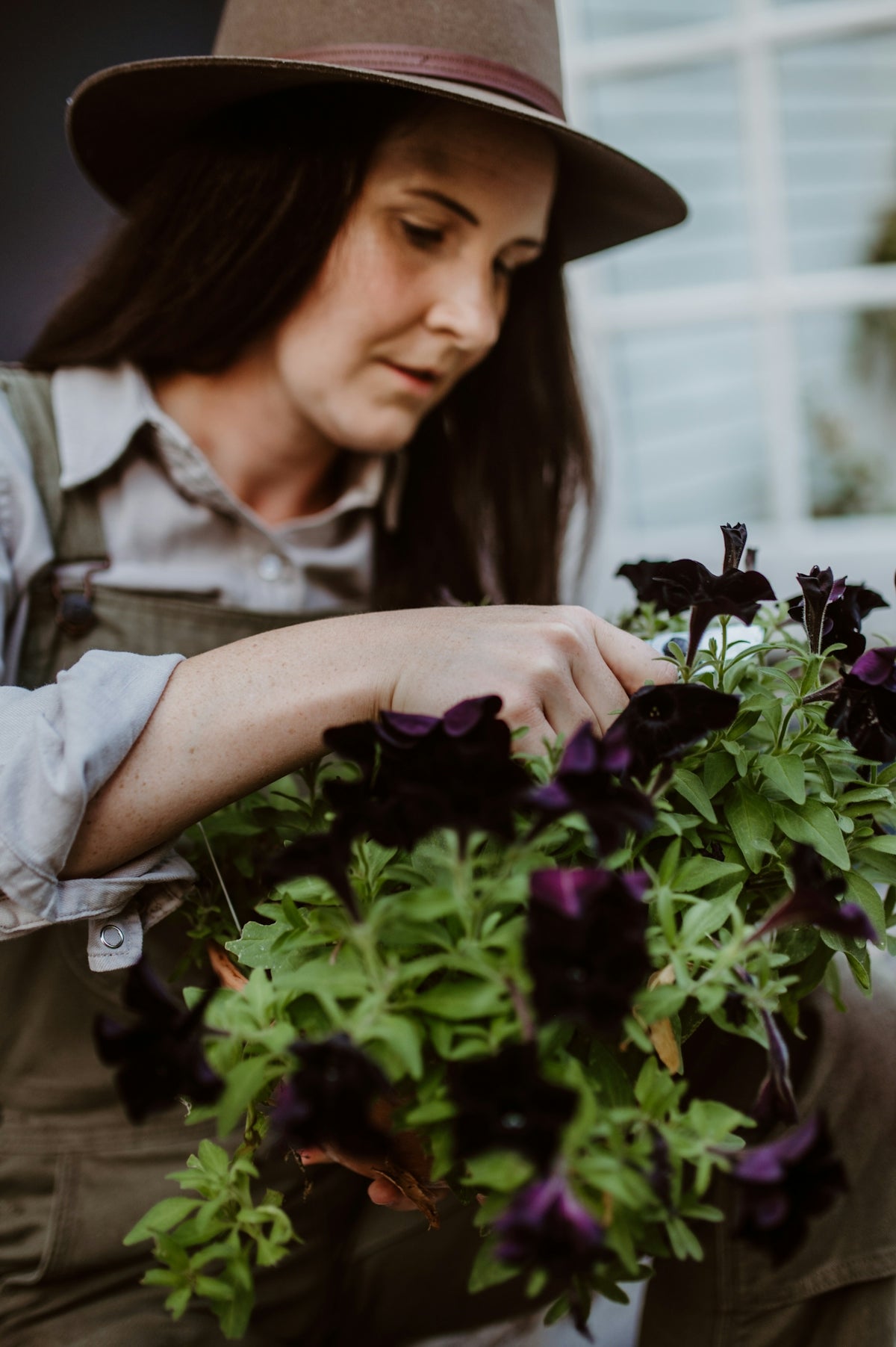A woman wearing a hat and holding a bunch of flowers