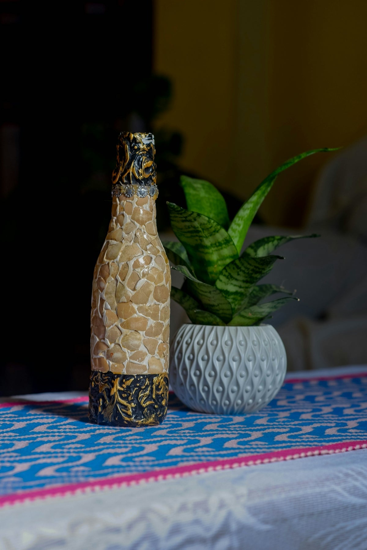 Decorated bottle and potted plant on table