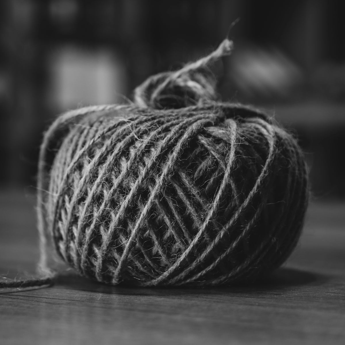 A monochrome ball of rustic twine on a wooden surface.